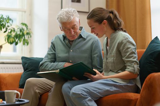 A young woman shows a photo album to an elderly woman.