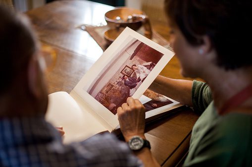 Person examining an old photo album at a wooden table.