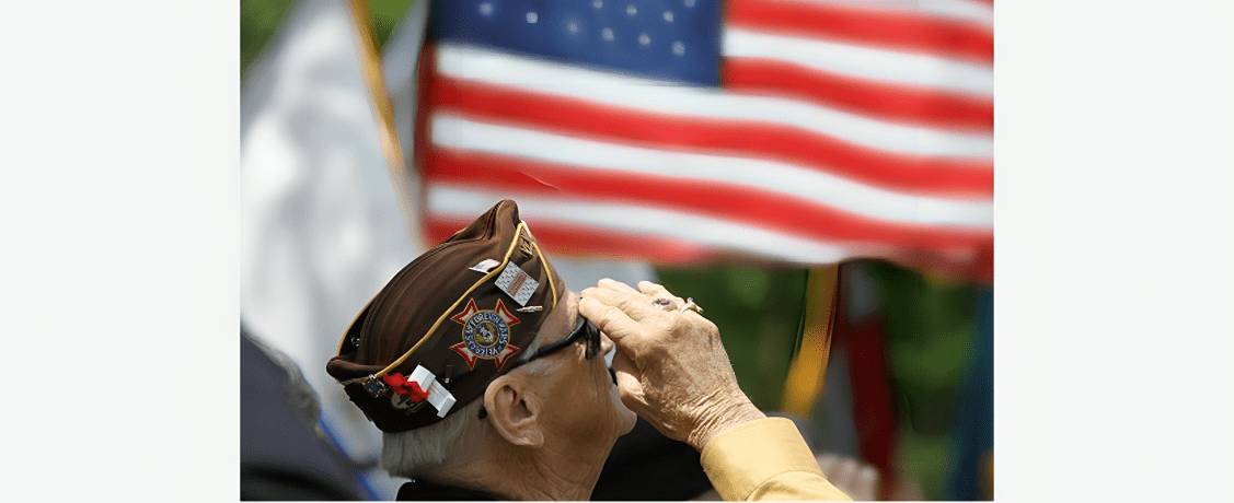 A veteran salutes with the American flag in the background.