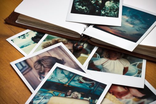 A collection of vintage photographs and a photo album on a table.